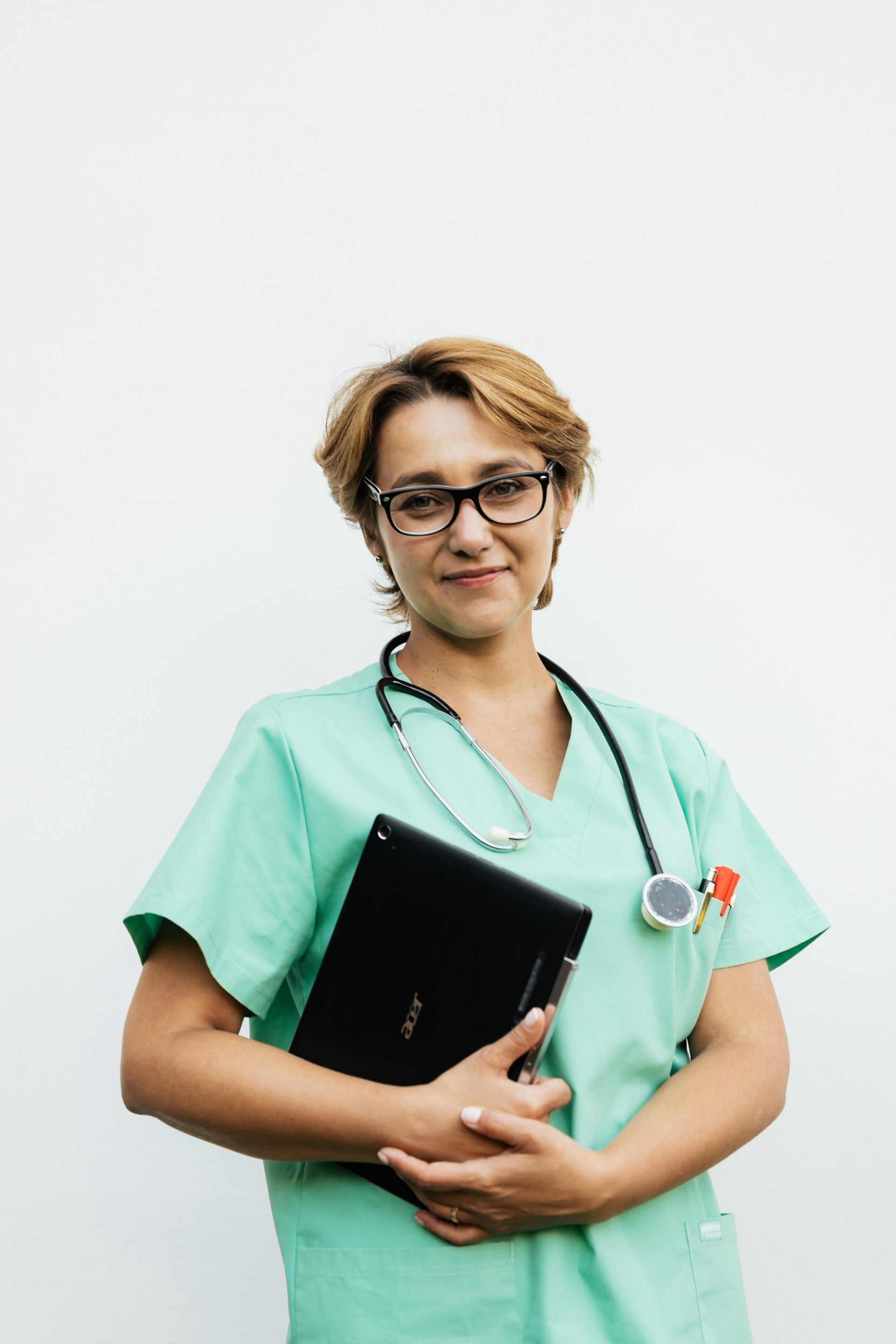 Confident female nurse with eyeglasses holding a tablet and stethoscope. Ideal for healthcare-related content.